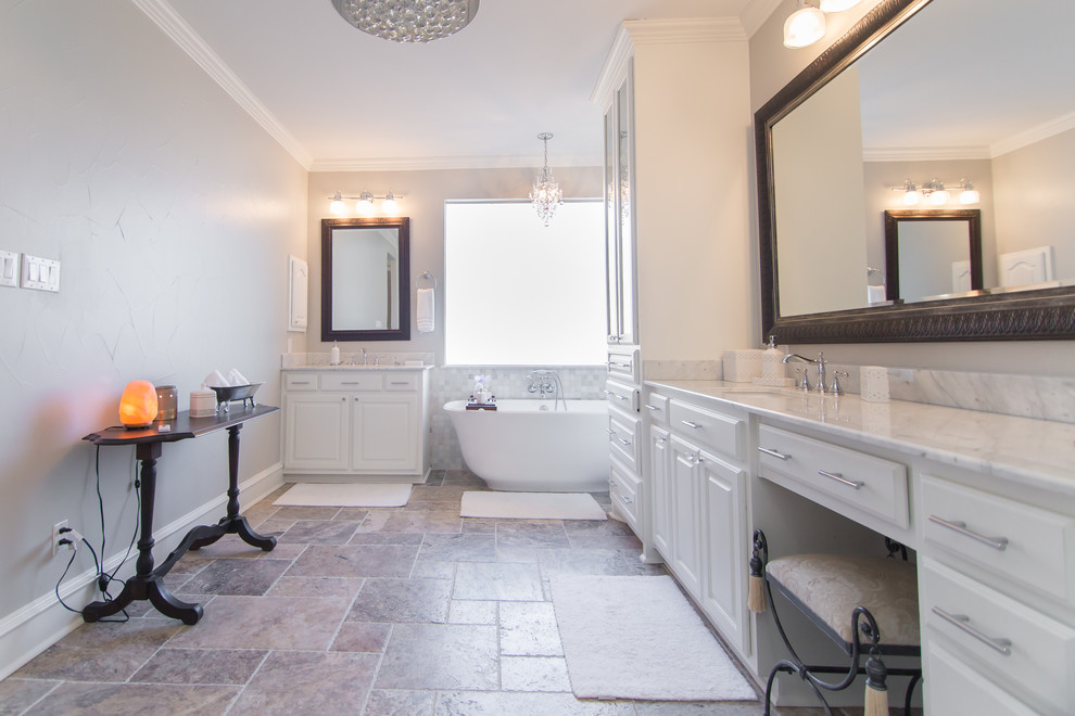 Klassisk inredning av ett stort vit vitt en-suite badrum, med vita skåp, ett fristående badkar, en dubbeldusch, en toalettstol med separat cisternkåpa, grå väggar, travertin golv, ett undermonterad handfat, marmorbänkskiva, grått golv, dusch med gångjärnsdörr, luckor med glaspanel, vit kakel och stenkakel
