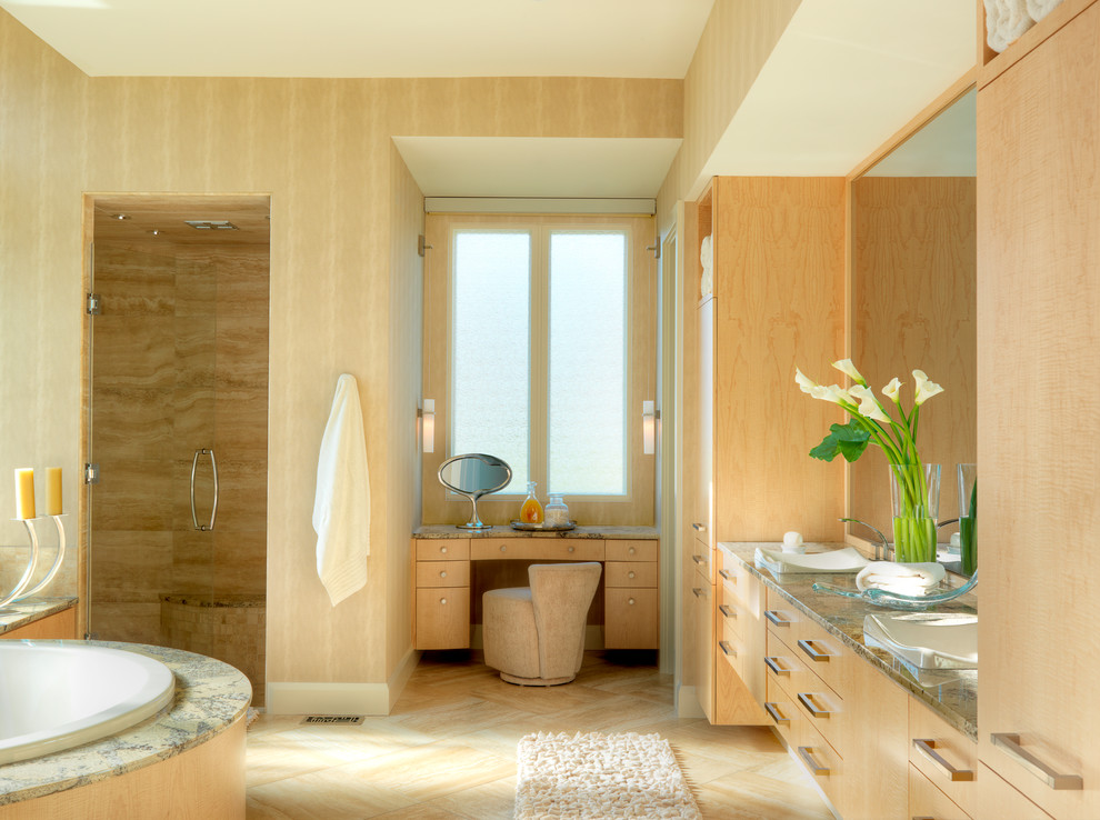 Inredning av ett modernt badrum, med skåp i ljust trä, granitbänkskiva, ett fristående handfat, släta luckor, ett platsbyggt badkar, en dusch i en alkov och beige kakel