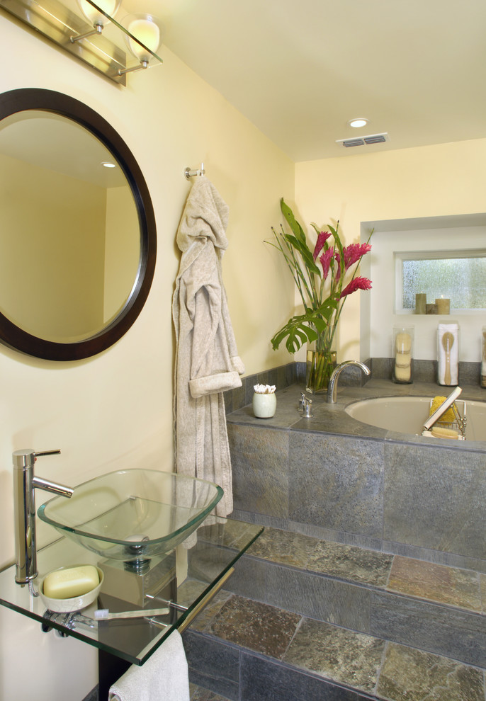 Inredning av ett modernt mellanstort en-suite badrum, med ett undermonterat badkar, beige väggar, ett fristående handfat, bänkskiva i glas, grå kakel, stenkakel, skiffergolv och flerfärgat golv