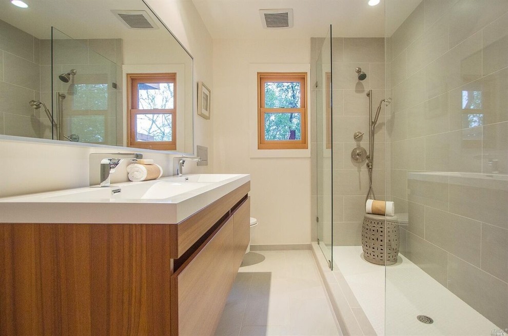 Пример оригинального дизайна: главная ванная комната среднего размера в стиле модернизм с плоскими фасадами, светлыми деревянными фасадами, открытым душем, белыми стенами, полом из керамогранита, монолитной раковиной, столешницей из искусственного камня и открытым душем