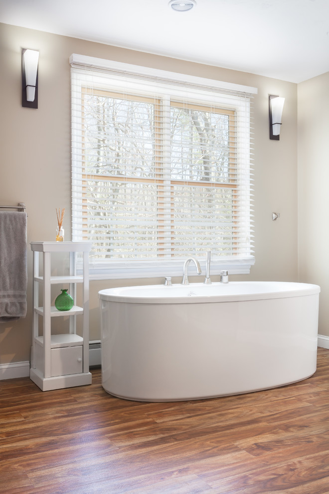 Imagen de cuarto de baño principal moderno grande con bañera exenta, paredes beige y suelo de madera en tonos medios