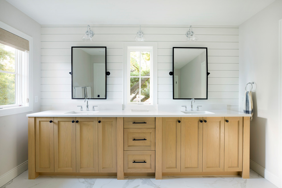 Diseño de cuarto de baño principal de estilo de casa de campo con armarios con paneles empotrados, puertas de armario de madera clara, paredes blancas, lavabo bajoencimera, suelo blanco, encimeras blancas y ventanas