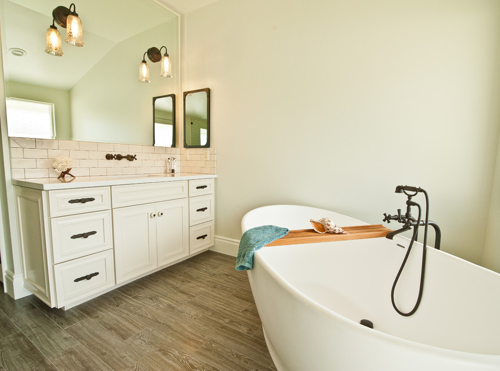 Large coastal ensuite bathroom in Orange County with raised-panel cabinets, white cabinets, a freestanding bath, a built-in shower, multi-coloured tiles, stone tiles, beige walls, ceramic flooring, a submerged sink and engineered stone worktops.