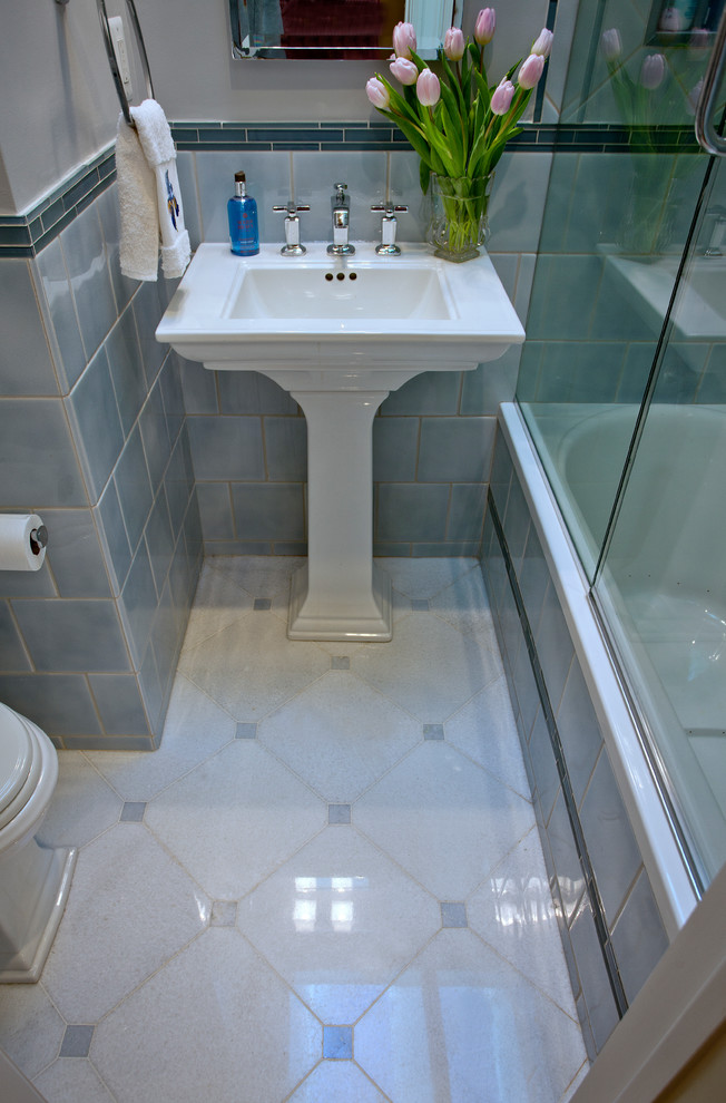 Bild på ett litet vintage badrum, med ett piedestal handfat, ett badkar i en alkov, en dusch i en alkov, en toalettstol med separat cisternkåpa, blå kakel, porslinskakel, blå väggar och marmorgolv