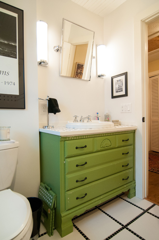 Klassisches Badezimmer mit verzierten Schränken, grünen Schränken, Toilette mit Aufsatzspülkasten, schwarz-weißen Fliesen, Keramikfliesen, weißer Wandfarbe, Porzellan-Bodenfliesen, Einbauwaschbecken und gefliestem Waschtisch in Atlanta