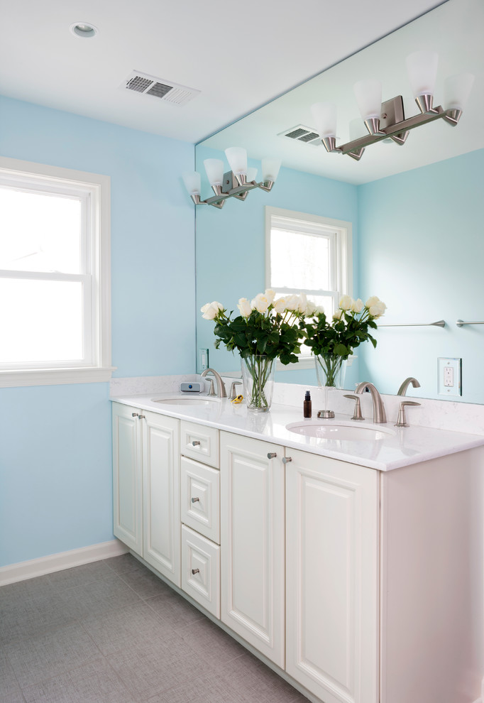 Idée de décoration pour une salle de bain tradition avec des portes de placard blanches et un mur bleu.