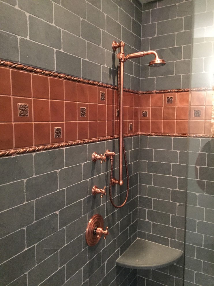 Cette image montre une grande salle de bain principale rustique avec une baignoire indépendante, une douche d'angle, un carrelage noir, un carrelage de pierre, un sol en ardoise et un mur gris.