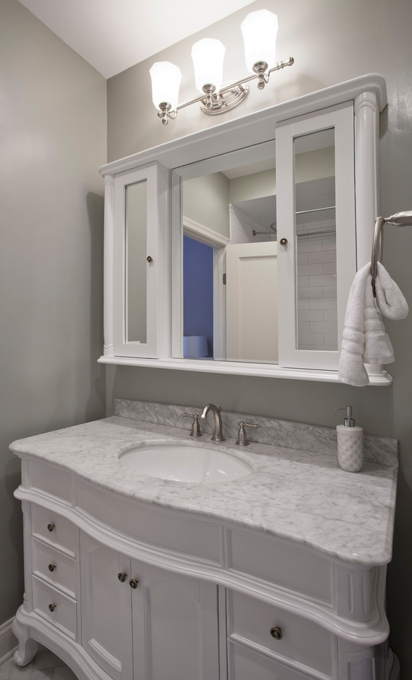 Bild på ett litet vintage en-suite badrum, med möbel-liknande, vita skåp, ett badkar med tassar, en dusch/badkar-kombination, en toalettstol med separat cisternkåpa, vit kakel, tunnelbanekakel, gröna väggar, marmorgolv, ett undermonterad handfat och marmorbänkskiva