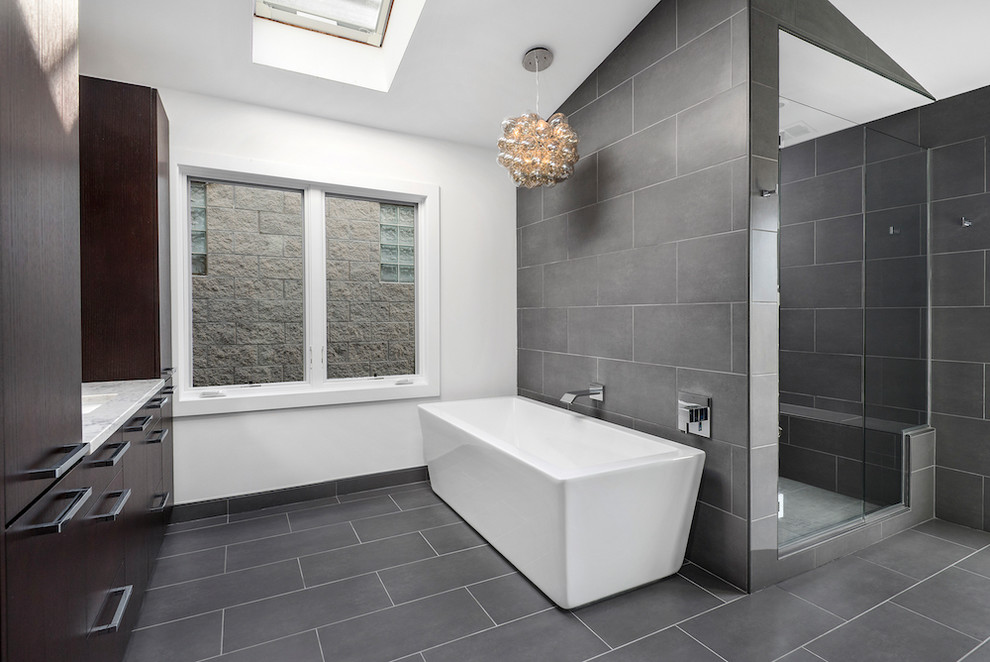На фото: главная ванная комната в современном стиле с отдельно стоящей ванной, двойным душем, серой плиткой и белыми стенами с