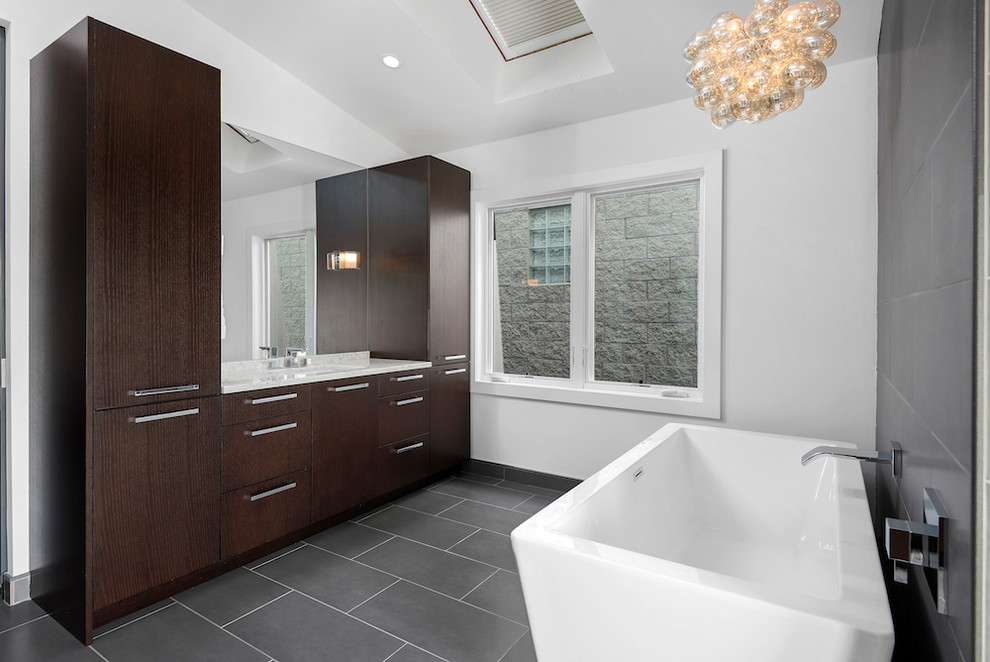 Modern inredning av ett en-suite badrum, med ett fristående badkar, en dubbeldusch, grå kakel och vita väggar