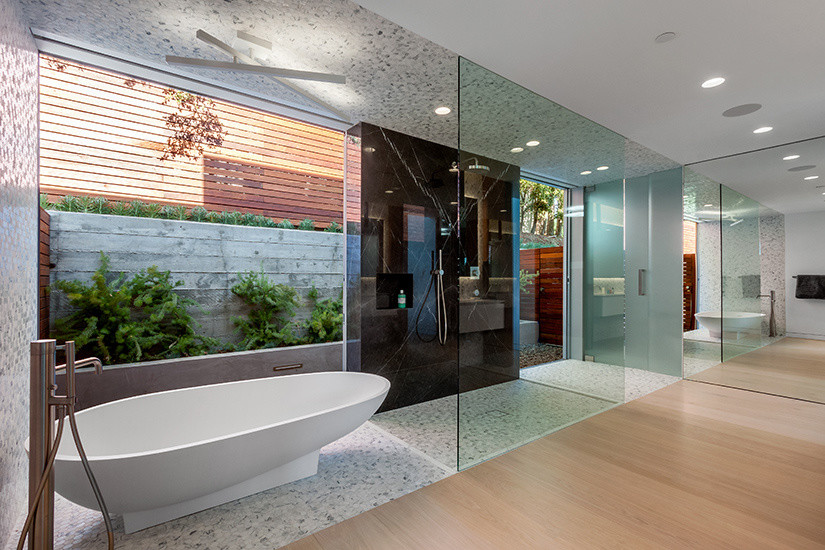 На фото: огромная главная ванная комната в стиле модернизм с отдельно стоящей ванной, душевой комнатой, серой плиткой, белой плиткой, каменной плиткой, белыми стенами и светлым паркетным полом с