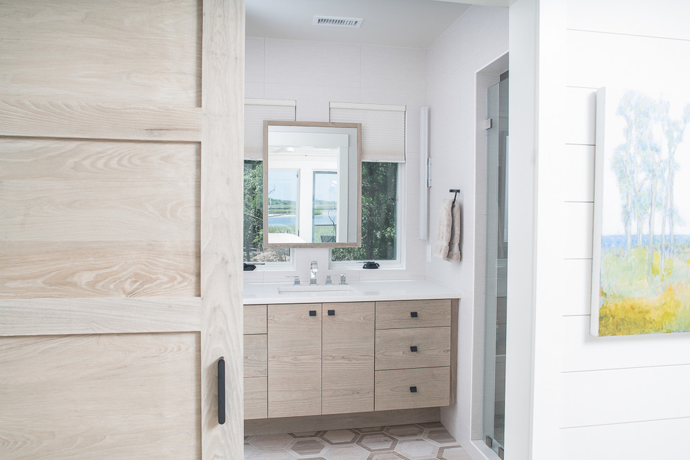This is an example of a large beach style ensuite bathroom in Other with flat-panel cabinets, light wood cabinets, an alcove shower, beige tiles, porcelain tiles, beige walls, mosaic tile flooring, a submerged sink, solid surface worktops, brown floors, a hinged door and white worktops.