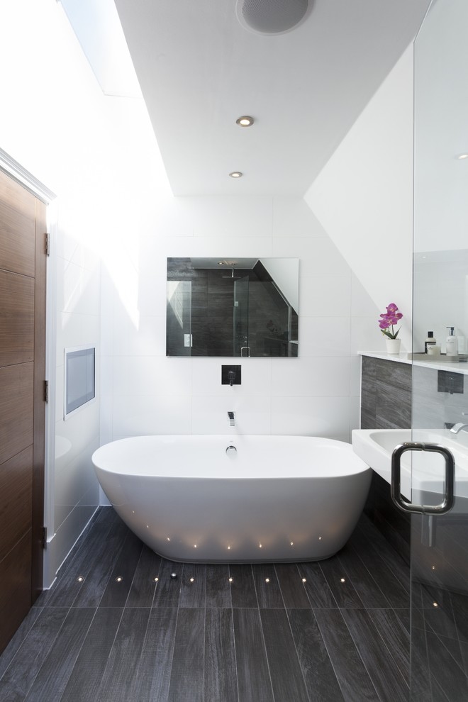 Стильный дизайн: ванная комната в современном стиле с отдельно стоящей ванной, белыми стенами, темным паркетным полом и подвесной раковиной - последний тренд