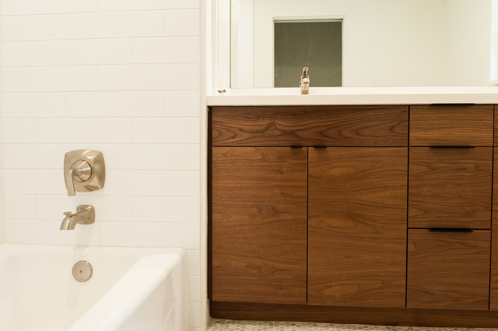 Imagen de cuarto de baño infantil minimalista pequeño con armarios con paneles lisos, puertas de armario de madera en tonos medios, bañera empotrada, sanitario de dos piezas, baldosas y/o azulejos blancos, baldosas y/o azulejos de porcelana, paredes blancas, suelo con mosaicos de baldosas, lavabo bajoencimera, encimera de acrílico, suelo gris y encimeras blancas