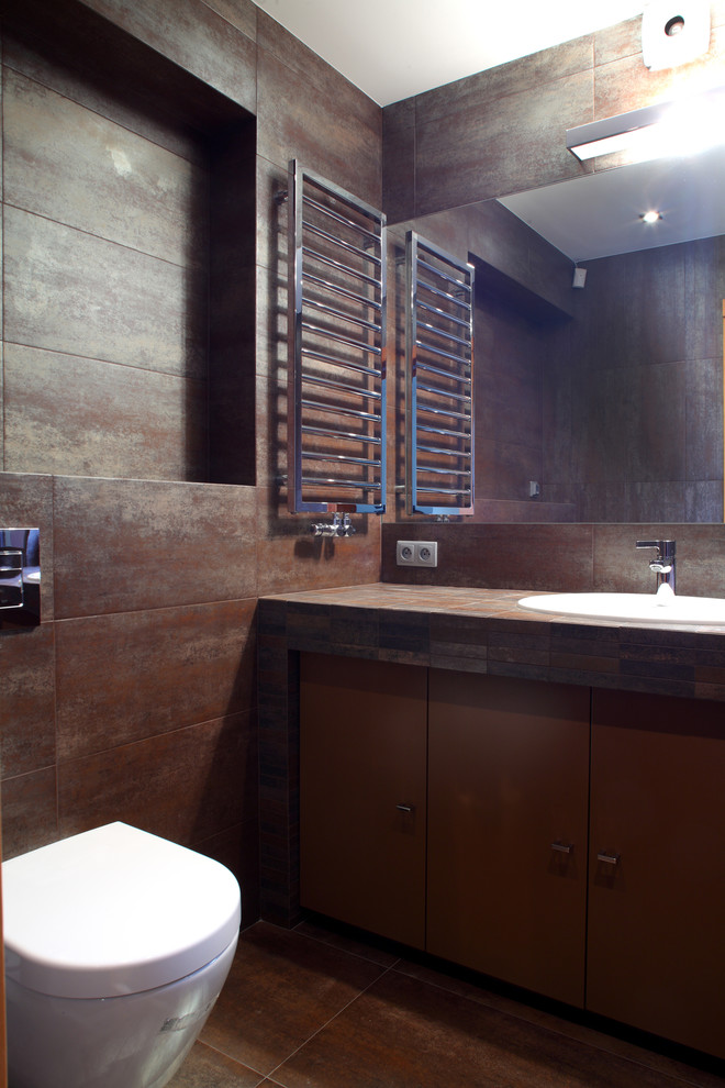 Foto på ett industriellt badrum, med ett nedsänkt handfat, möbel-liknande, bruna skåp, kaklad bänkskiva, en öppen dusch och en vägghängd toalettstol