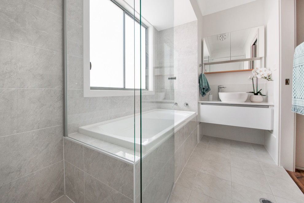Bild på ett litet funkis vit vitt en-suite badrum, med möbel-liknande, skåp i mellenmörkt trä, ett platsbyggt badkar, en dubbeldusch, en vägghängd toalettstol, grå kakel, keramikplattor, grå väggar, cementgolv, ett undermonterad handfat, bänkskiva i akrylsten, grått golv och dusch med gångjärnsdörr