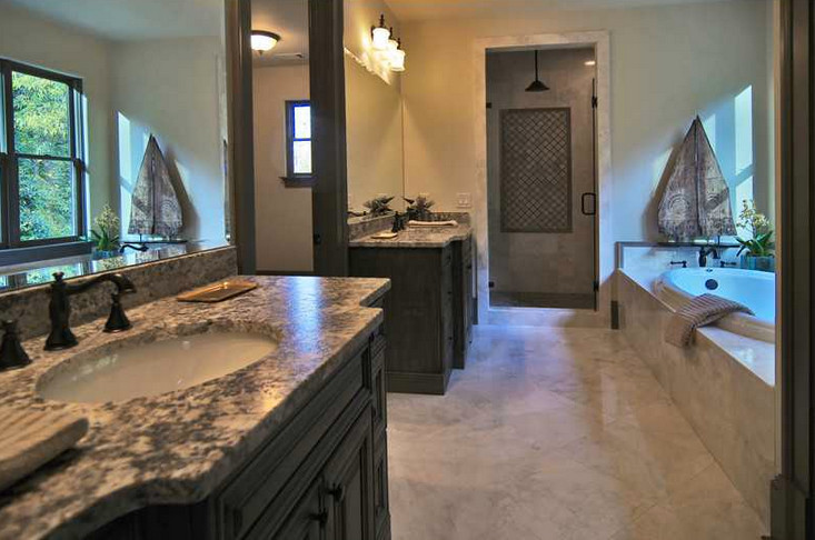 На фото: большая главная ванная комната в средиземноморском стиле с коричневыми фасадами, накладной ванной, угловым душем, бежевыми стенами, мраморным полом, накладной раковиной, столешницей из гранита, белым полом и душем с распашными дверями
