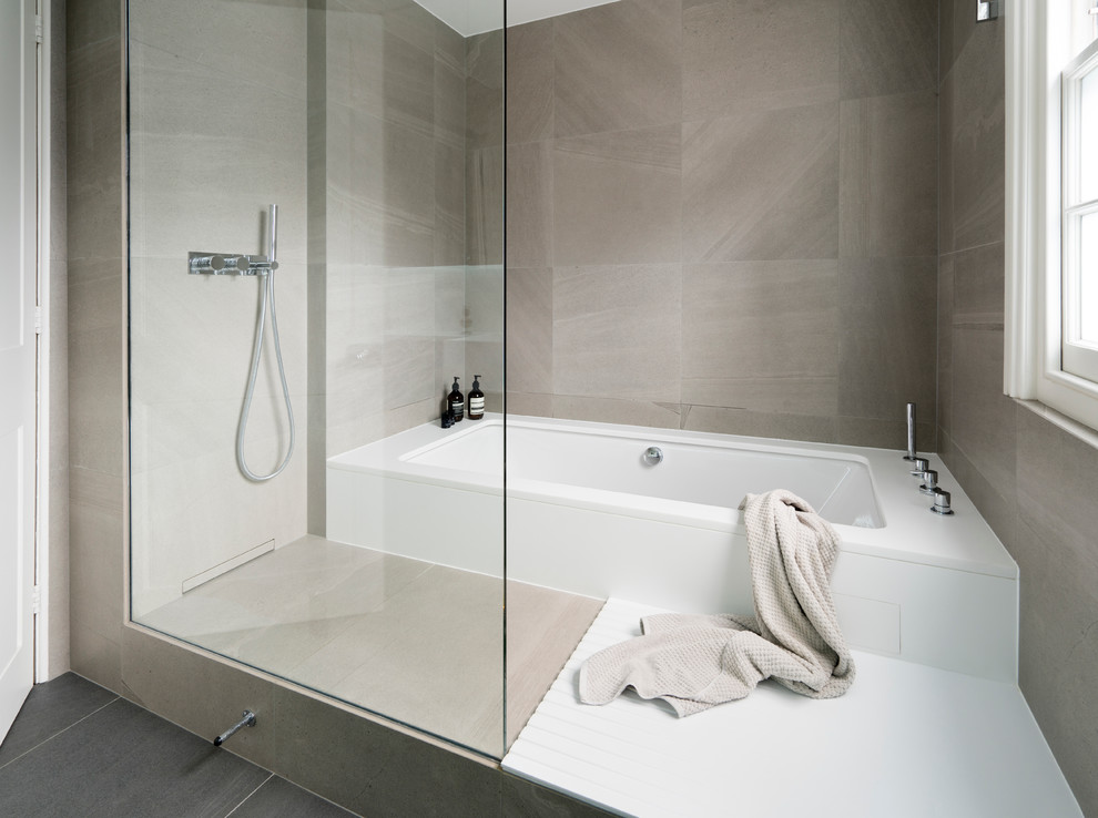 Contemporary family bathroom in London with a built-in bath, a wall mounted toilet, grey tiles, porcelain tiles, grey walls, porcelain flooring and a wall-mounted sink.