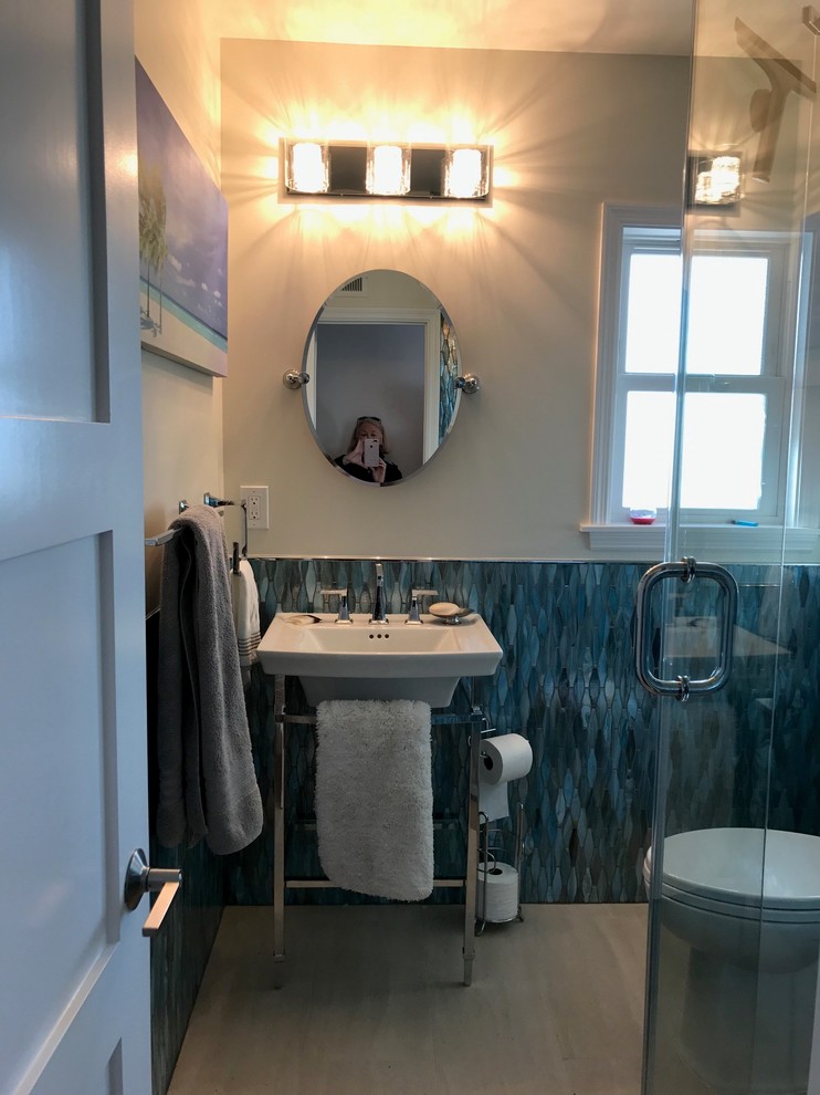Cette image montre une salle d'eau marine de taille moyenne avec une douche d'angle, WC à poser, un carrelage bleu, un mur beige, un sol en carrelage de porcelaine, un carrelage en pâte de verre et un plan vasque.