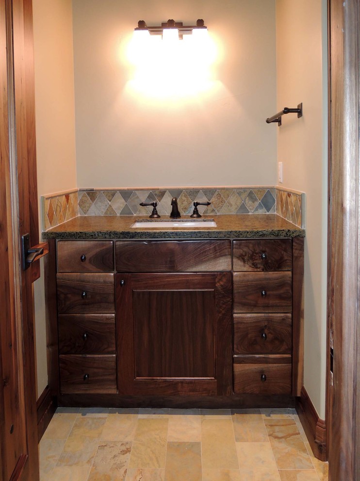 Bild på ett litet amerikanskt badrum med dusch, med skåp i mörkt trä, luckor med infälld panel, flerfärgad kakel och granitbänkskiva