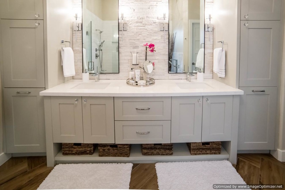 Inredning av ett klassiskt stort en-suite badrum, med skåp i shakerstil, vita skåp, vit kakel, stenkakel, vita väggar, ljust trägolv, ett undermonterad handfat och bänkskiva i akrylsten