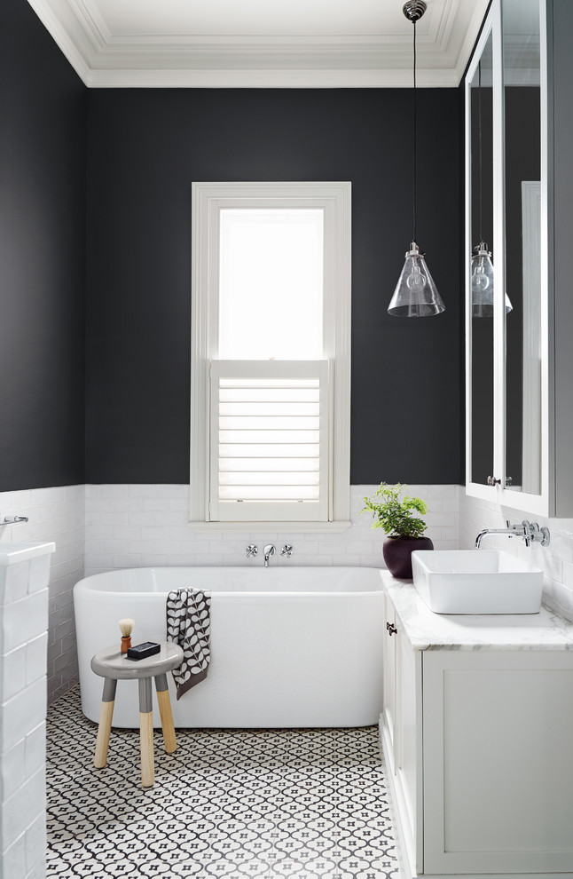 Example of a mid-sized trendy black and white tile freestanding bathtub design in Melbourne with white cabinets