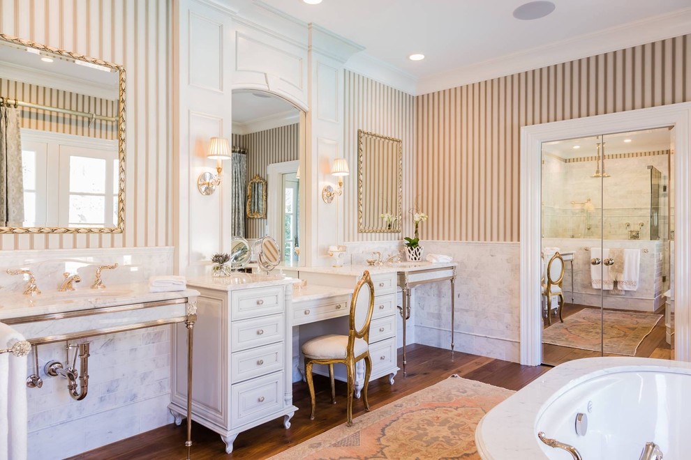 Aménagement d'une grande salle de bain principale classique avec une baignoire indépendante, une douche d'angle, un sol en bois brun, un lavabo encastré et un plan de toilette en marbre.