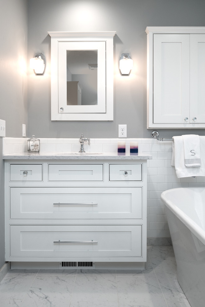 Inspiration for a mid-sized transitional master white tile and ceramic tile ceramic tile and white floor freestanding bathtub remodel in Other with shaker cabinets, white cabinets, gray walls, an undermount sink, quartz countertops and a hinged shower door