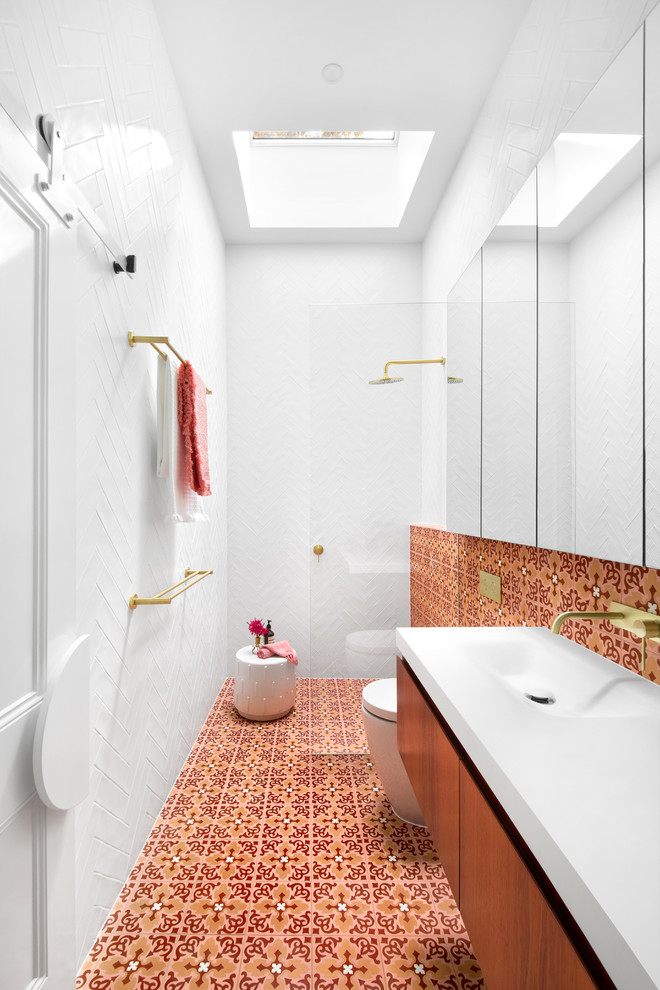 Cette photo montre une salle d'eau scandinave en bois brun avec un placard à porte plane, une douche à l'italienne, un carrelage orange, un carrelage rouge, un carrelage blanc, un lavabo intégré, un sol multicolore, aucune cabine et un plan de toilette blanc.