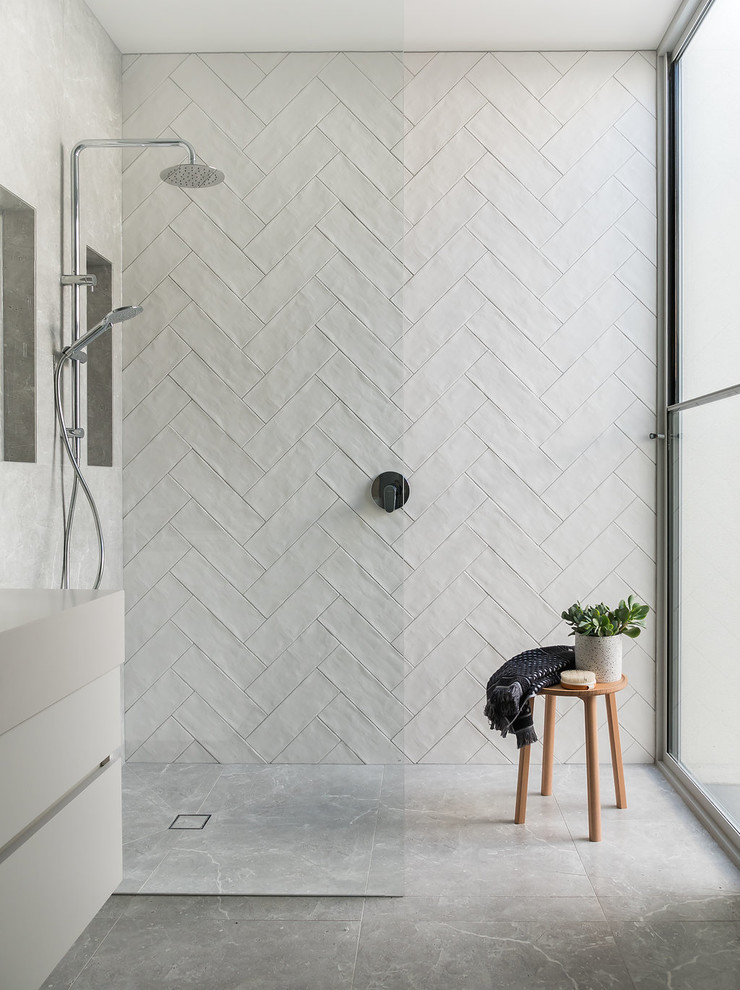 Modernes Badezimmer mit flächenbündigen Schrankfronten, weißen Schränken, bodengleicher Dusche, weißen Fliesen, weißer Wandfarbe, grauem Boden, offener Dusche und weißer Waschtischplatte in Melbourne