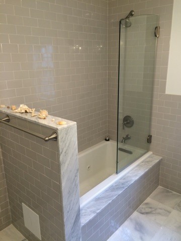 Réalisation d'une salle d'eau tradition de taille moyenne avec un placard en trompe-l'oeil, des portes de placard blanches, une baignoire en alcôve, un combiné douche/baignoire, WC à poser, un carrelage gris, un carrelage métro, un mur blanc, un sol en marbre, un lavabo encastré et un plan de toilette en marbre.