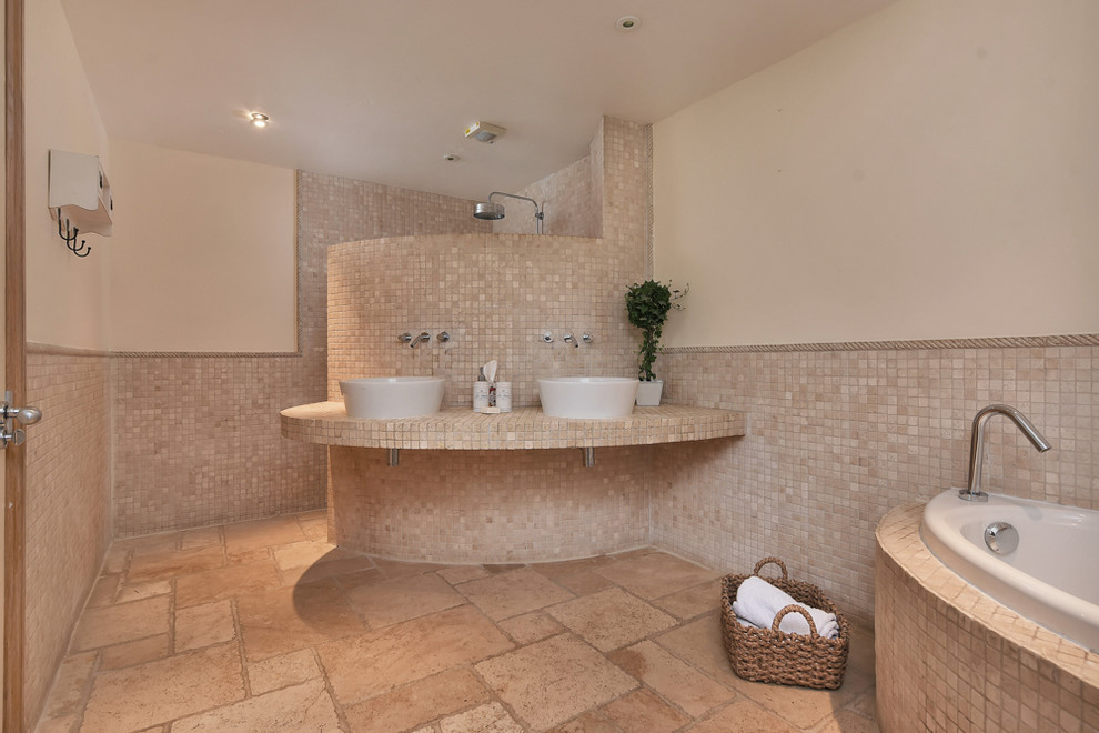 На фото: ванная комната среднего размера в средиземноморском стиле с угловой ванной, душевой комнатой, бежевой плиткой, плиткой мозаикой, бежевыми стенами, настольной раковиной, бежевым полом, открытым душем и бежевой столешницей с