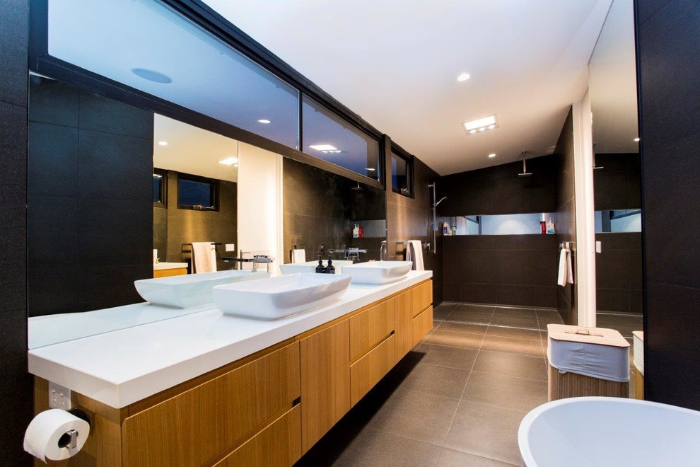 Medium sized contemporary shower room bathroom in Melbourne with a built-in sink, medium wood cabinets, a freestanding bath, a walk-in shower, a bidet, grey tiles, porcelain tiles, brown walls, porcelain flooring, flat-panel cabinets and an open shower.