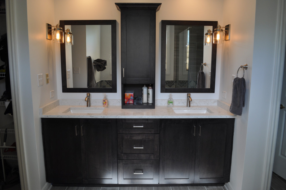 На фото: большая главная ванная комната с фасадами в стиле шейкер, черными фасадами, отдельно стоящей ванной, угловым душем, унитазом-моноблоком, серой плиткой, керамической плиткой, серыми стенами, полом из керамической плитки, врезной раковиной, столешницей из искусственного кварца, серым полом, душем с распашными дверями, белой столешницей, сиденьем для душа, тумбой под две раковины, встроенной тумбой, сводчатым потолком и панелями на стенах с
