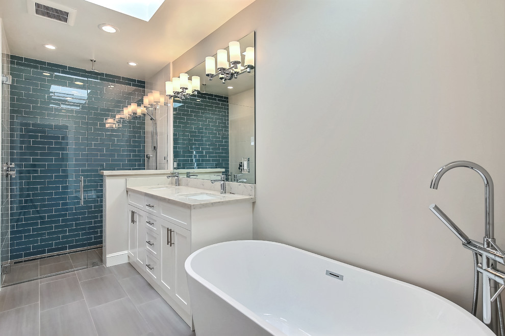 Foto de cuarto de baño principal actual de tamaño medio con armarios estilo shaker, puertas de armario blancas, bañera exenta, ducha empotrada y lavabo bajoencimera