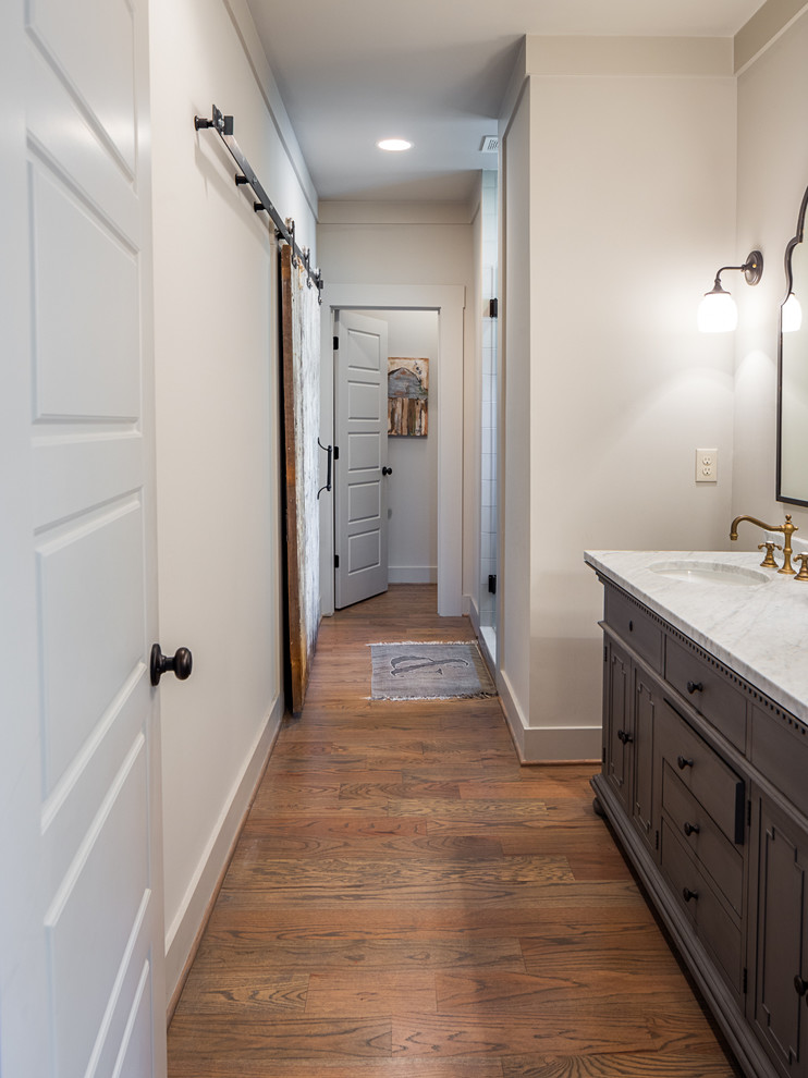 Alcove shower - mid-sized traditional master gray tile and ceramic tile medium tone wood floor alcove shower idea in Birmingham with an undermount sink, raised-panel cabinets, gray cabinets, granite countertops, a two-piece toilet and gray walls
