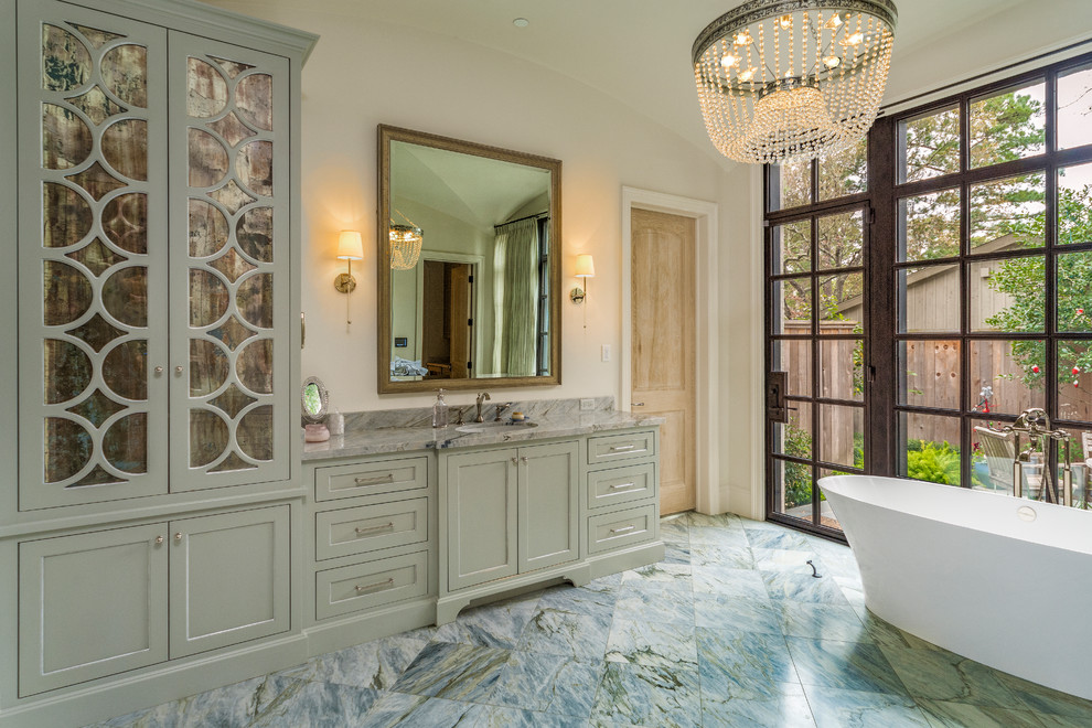 Diseño de cuarto de baño principal clásico renovado con armarios con paneles empotrados, puertas de armario verdes, bañera exenta, paredes beige, lavabo bajoencimera, suelo multicolor y encimeras grises