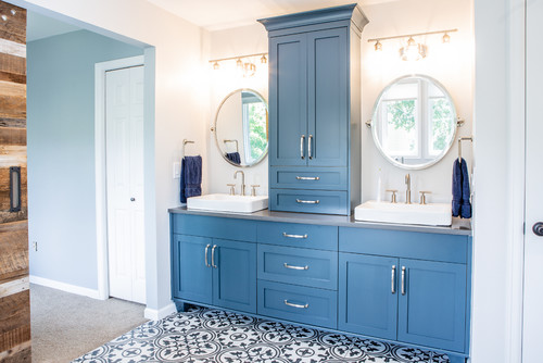 Bathroom Cabinets – blue shaker double vanity with center tower, round mirrors, vessel sinks, and patterned tile floor.