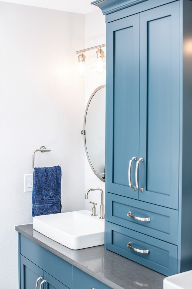 На фото: большая главная ванная комната в стиле неоклассика (современная классика) с фасадами в стиле шейкер, синими фасадами, отдельно стоящей ванной, угловым душем, унитазом-моноблоком, белой плиткой, керамической плиткой, серыми стенами, полом из керамической плитки, настольной раковиной, столешницей из искусственного кварца, разноцветным полом, душем с распашными дверями и серой столешницей