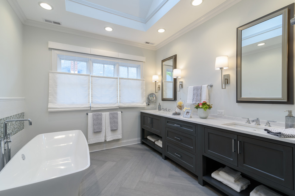 Idéer för ett stort klassiskt en-suite badrum, med möbel-liknande, ett fristående badkar, en dusch i en alkov, en toalettstol med separat cisternkåpa, tunnelbanekakel, grå väggar, klinkergolv i porslin, ett undermonterad handfat, bänkskiva i kvarts, dusch med gångjärnsdörr, grå skåp, vit kakel och grått golv