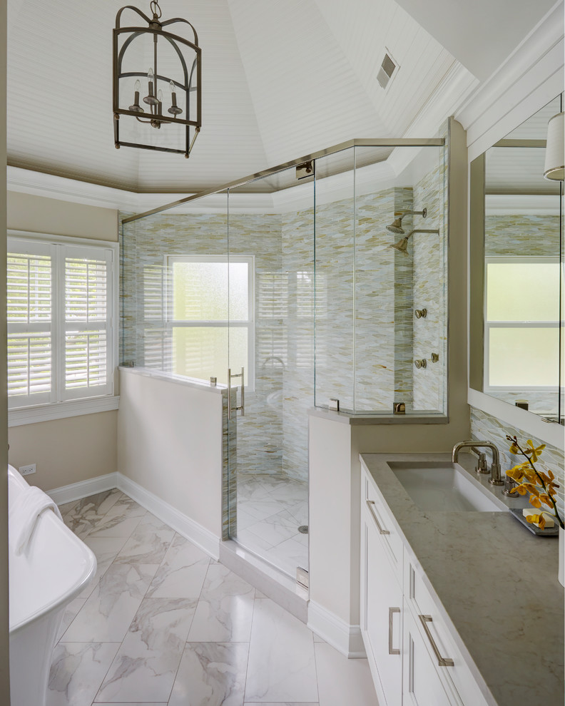Идея дизайна: главная ванная комната среднего размера в стиле неоклассика (современная классика) с фасадами с утопленной филенкой, белыми фасадами, отдельно стоящей ванной, двойным душем, унитазом-моноблоком, разноцветной плиткой, стеклянной плиткой, серыми стенами, мраморным полом, врезной раковиной, столешницей из искусственного кварца, белым полом, душем с распашными дверями и серой столешницей