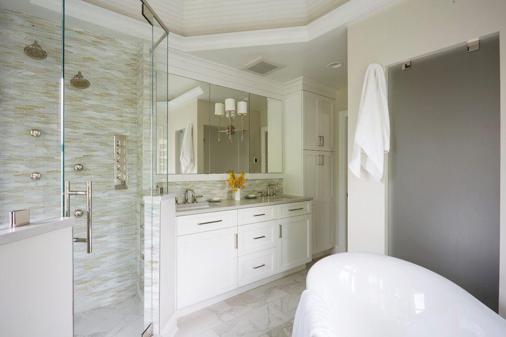 Идея дизайна: главная ванная комната среднего размера в стиле неоклассика (современная классика) с фасадами с утопленной филенкой, белыми фасадами, отдельно стоящей ванной, двойным душем, унитазом-моноблоком, разноцветной плиткой, стеклянной плиткой, серыми стенами, мраморным полом, врезной раковиной, столешницей из искусственного кварца, белым полом, душем с распашными дверями и серой столешницей