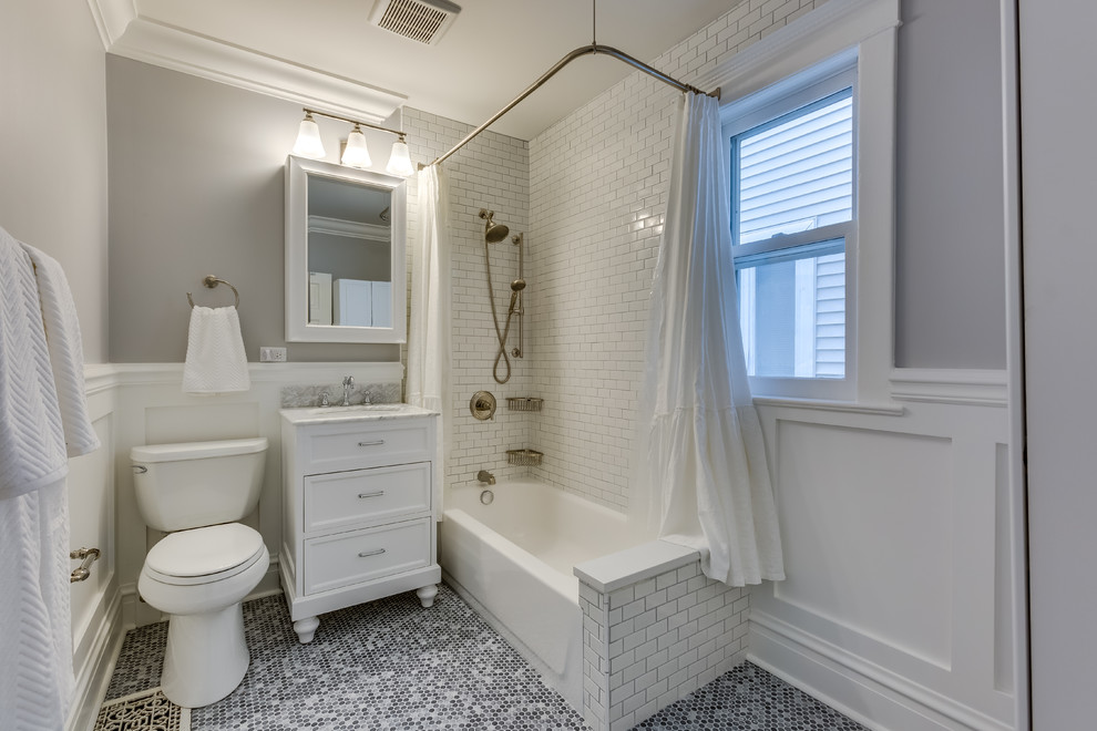 Exempel på ett stort klassiskt badrum, med luckor med infälld panel, vita skåp, ett badkar i en alkov, en dusch/badkar-kombination, en toalettstol med separat cisternkåpa, vit kakel, tunnelbanekakel, grå väggar, ett undermonterad handfat, marmorbänkskiva och flerfärgat golv