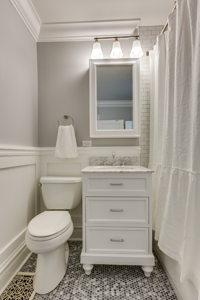 Пример оригинального дизайна: ванная комната среднего размера в классическом стиле с фасадами с утопленной филенкой, белыми фасадами, ванной в нише, душем над ванной, белой плиткой, плиткой кабанчик, серыми стенами, полом из мозаичной плитки, душевой кабиной, врезной раковиной, мраморной столешницей, серым полом и шторкой для ванной