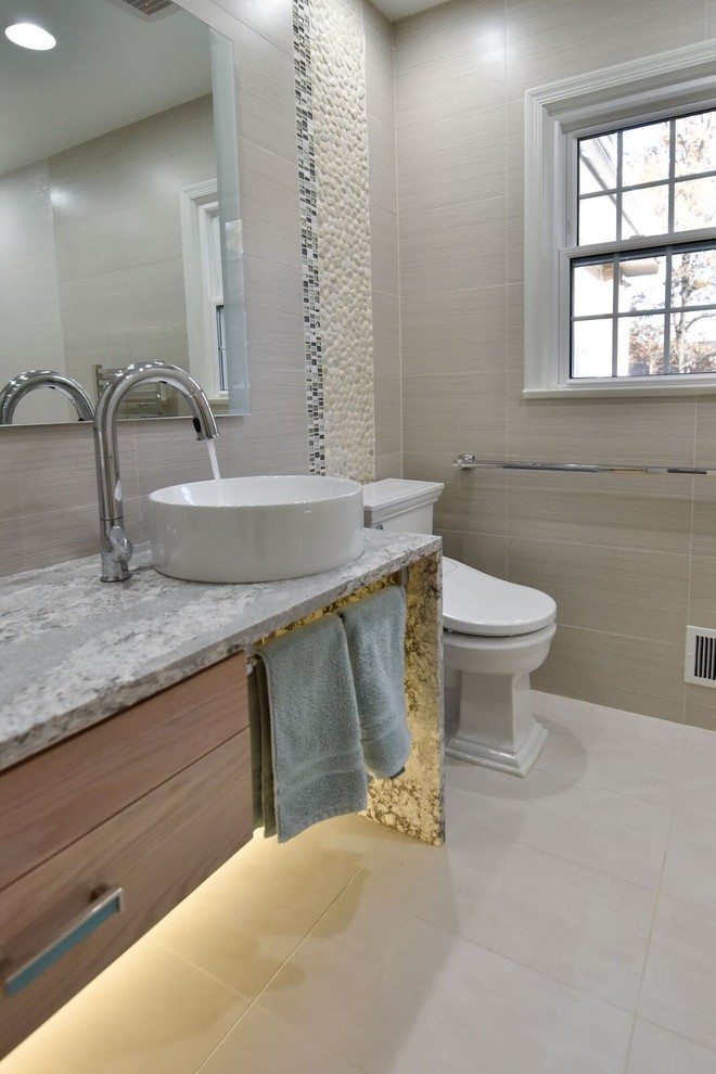 Large contemporary ensuite bathroom in DC Metro with glass-front cabinets, beige cabinets, a built-in shower, a two-piece toilet, beige tiles, ceramic tiles, beige walls, ceramic flooring, a vessel sink, quartz worktops, beige floors and a hinged door.