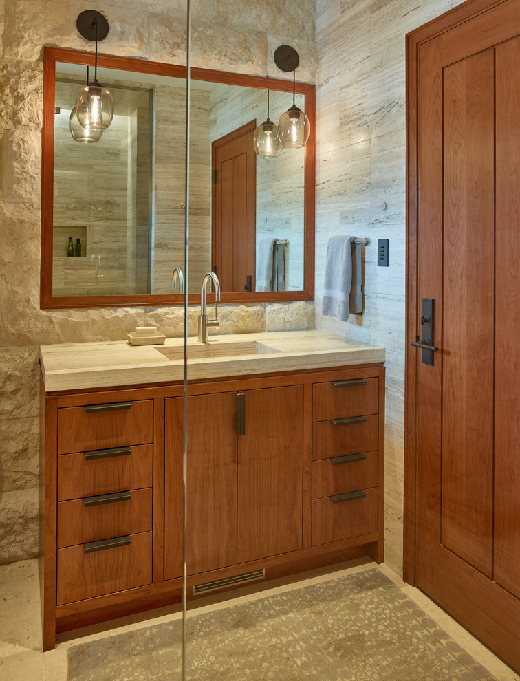 Пример оригинального дизайна: большая главная ванная комната в стиле модернизм с плоскими фасадами, фасадами цвета дерева среднего тона, серой плиткой, серыми стенами, монолитной раковиной, каменной плиткой, полом из травертина и мраморной столешницей