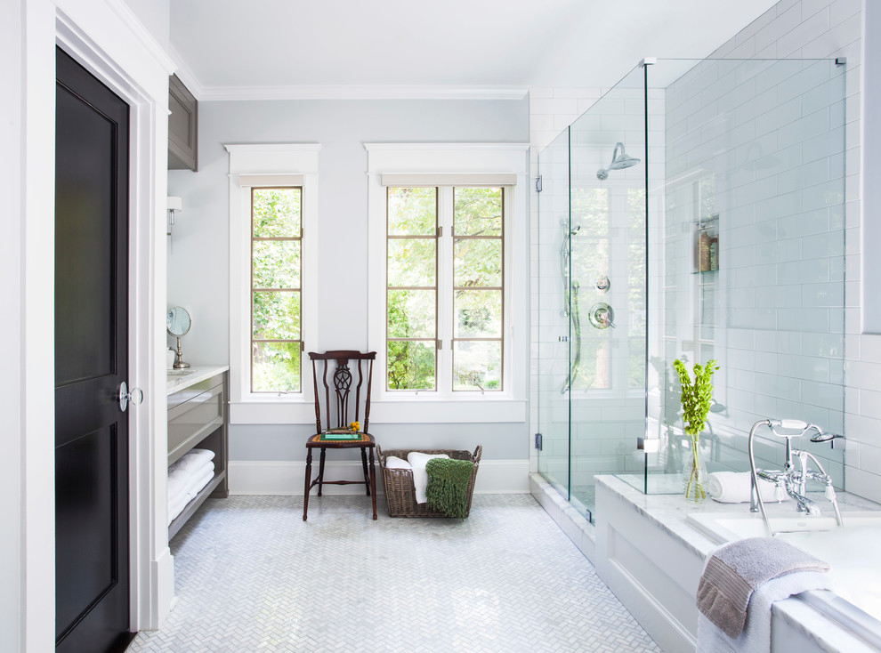 На фото: главная ванная комната среднего размера в стиле неоклассика (современная классика) с врезной раковиной, серыми фасадами, мраморной столешницей, накладной ванной, угловым душем, белой плиткой, плиткой кабанчик и серыми стенами