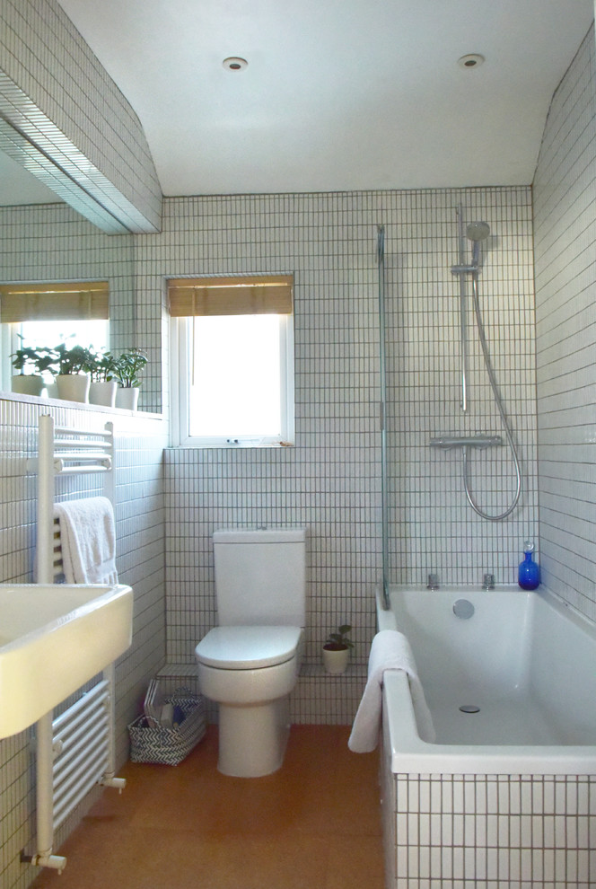 Aménagement d'une petite salle de bain pour enfant avec un placard à porte plane, des portes de placard blanches, une baignoire posée, un combiné douche/baignoire, WC séparés, un carrelage blanc, mosaïque, un mur blanc, un sol en liège et un lavabo suspendu.