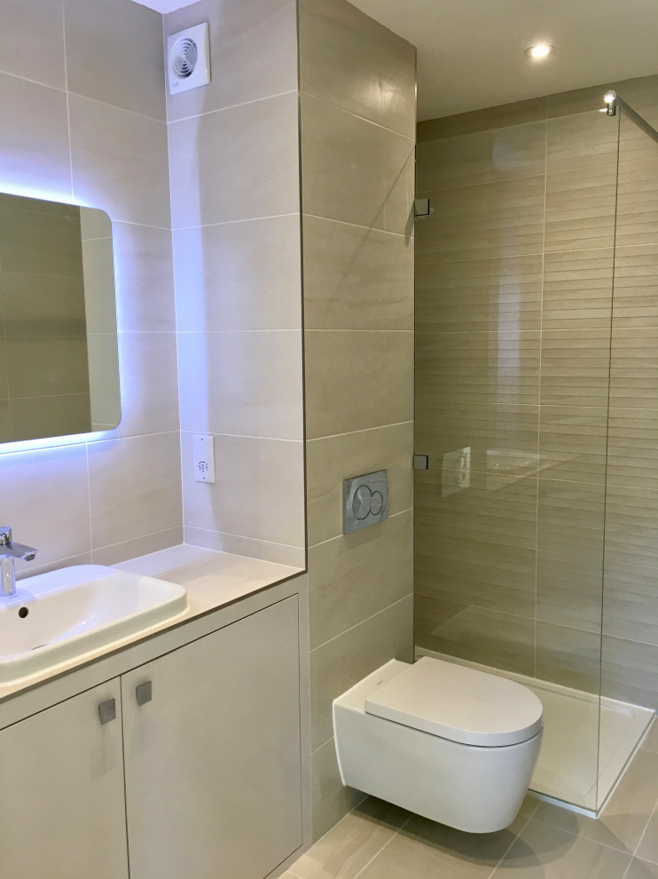 Photo of a small traditional ensuite bathroom in London with flat-panel cabinets, beige cabinets, a walk-in shower, a wall mounted toilet, beige tiles, porcelain tiles, beige walls, porcelain flooring, a built-in sink, tiled worktops, beige floors and beige worktops.