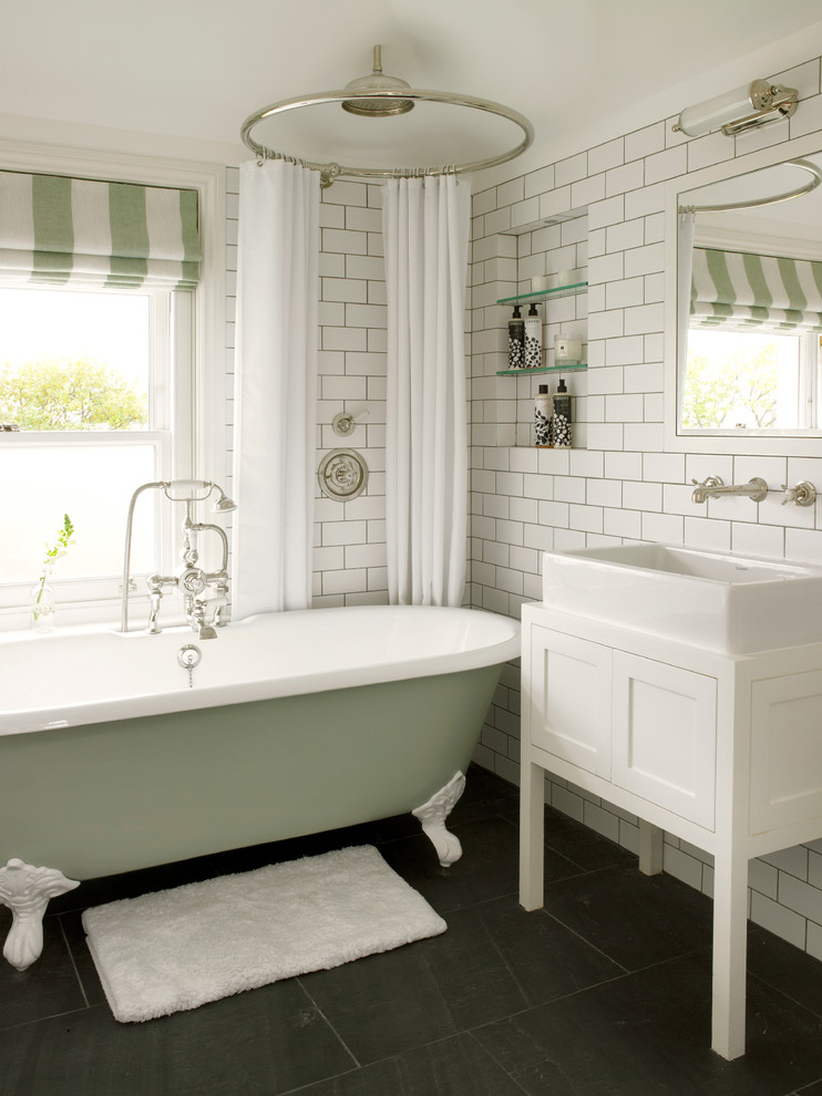 Klassisk inredning av ett litet vit vitt badrum för barn, med ett fristående handfat, ett badkar med tassar, vit kakel, tunnelbanekakel, vita skåp, en dusch/badkar-kombination, en vägghängd toalettstol, vita väggar, skiffergolv, träbänkskiva, grått golv, dusch med duschdraperi och skåp i shakerstil